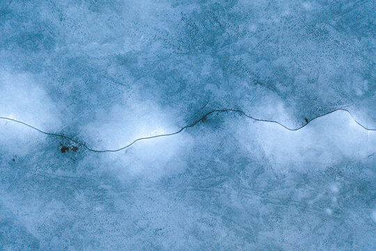 Aerial view of the frozen Neman river estuary in Kauno Mariu national park with a crack on the ice in early spring, Kaunas, Lithuania.