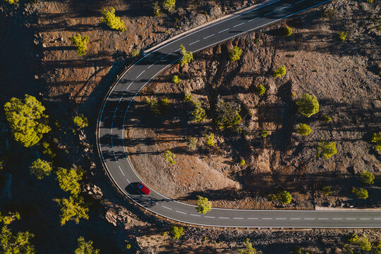 Aerial view of red vehicle driving on curvy mountain road in Tenerife, Canary islands, Spain.