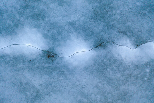Aerial view of the frozen Neman river estuary in Kauno Mariu national park with a crack on the ice in early spring, Kaunas, Lithuania.