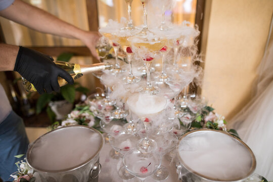 Horizontal photo of a hand that pours champagne into a wedding fountain