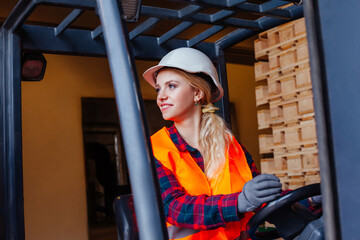 Smiling woman driving forklift truck at the warehouse