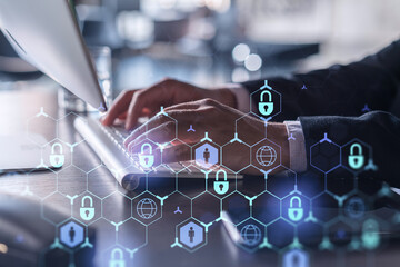 A programmer is typing a code on computer to protect a cyber security from hacker attacks and save clients confidential data. Padlock Hologram icons over the typing hands. Formal wear.