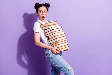 Portrait of impressed pretty person arms hold stack book open mouth look camera isolated on purple...