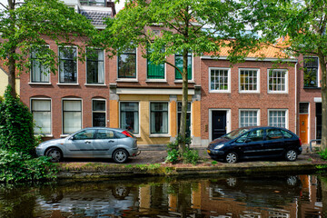 Fototapeta na wymiar Cars on canal embankment in street of Delft. Delft, Netherlands
