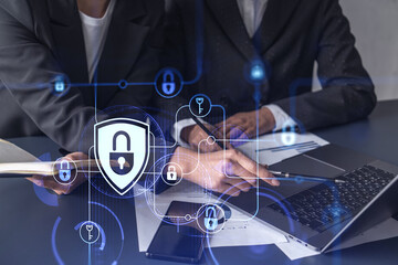 Two businesswomen working on the project to protect cyber security of international company. Padlock Hologram icons over the table with documents.