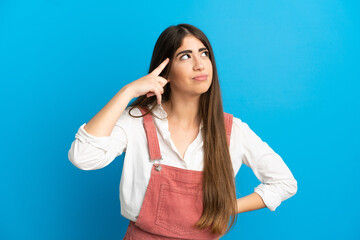 Fototapeta premium Young caucasian woman isolated on blue background making the gesture of madness putting finger on the head
