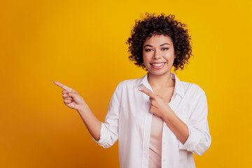 Portrait of young business woman pointing fingers empty space advise novelty on yellow background