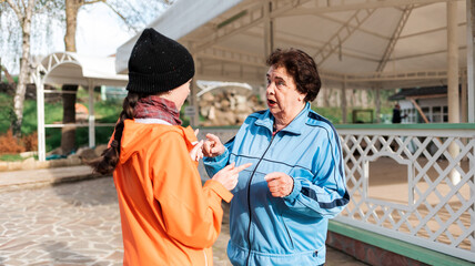 A grandmother and an adult granddaughter communicate on the street. Outdoor. The concept of the...