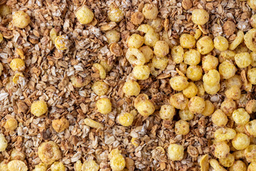 Organic homemade roasted crispy granola cereal with oatmeal and flaxseed flakes and crunchy corn balls and rings. Top view, flat lay muesli background texture