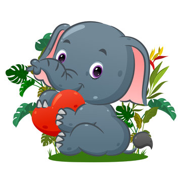 The happy elephant is sitting and holding the love doll on her hand in the park