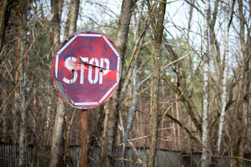 Old rusty stop sign among trees in radioactive zone in the Duga radar area near the Pripyat city....