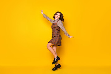 Fototapeta na wymiar Full length body size photo of schoolgirl dancing at party wearing plaid uniform isolated vibrant yellow color background