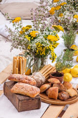 Bread of ciabatta, lemons, flowers on a picnic