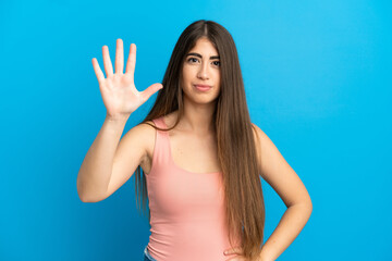 Young caucasian woman isolated on blue background counting five with fingers