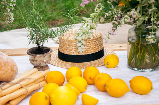 Straw hat among flowers and lemons on a picnic
