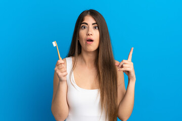 Obraz premium Young caucasian woman brushing teeth isolated on blue background intending to realizes the solution while lifting a finger up