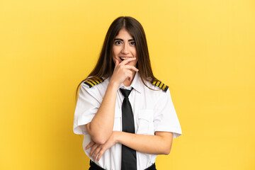 Airplane pilot isolated on yellow background surprised and shocked while looking right