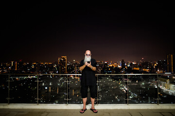 Fototapeta na wymiar Portrait of mature man with gray beard outdoors at night using phone