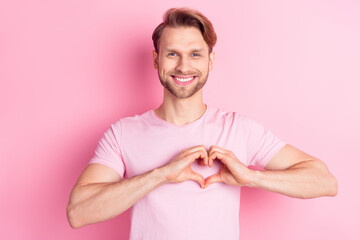 Portrait of cheerful man hands fingers make show heart figure toothy smile isolated on pink color...