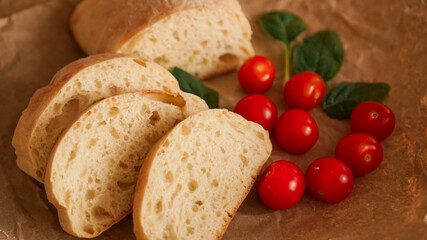 Ciabatta slices and cherry tomatoes on craft paper.