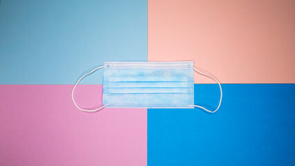 Surgical mask with rubber ear straps. Typical 3-ply surgical mask to cover the mouth and nose. Procedure mask from bacteria on a blue pink background. Negative space or copy space for text.