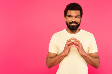sly african american man looking away isolated on pink