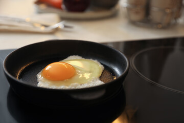 Frying pan with fresh egg on stove, space for text