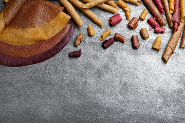 Delicious fruit leather rolls on grey table, flat lay. Space for text