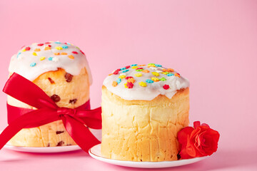 Delicious Easter cakes panettone decorated with ribbon and flowers on pink background.