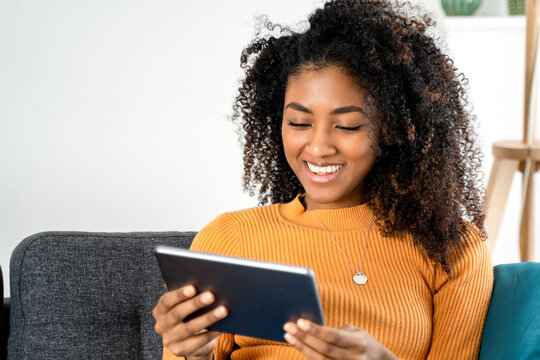 Black african american holding a digital tablet on the sofa