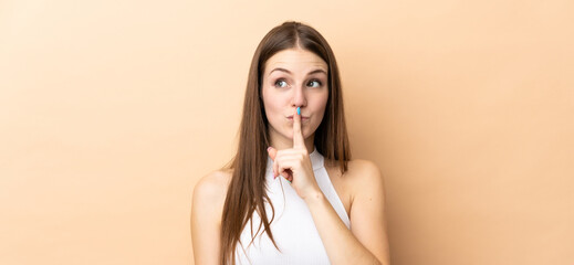 Young caucasian woman isolated on beige background showing a sign of silence gesture putting finger...
