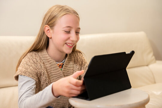 UK, Surrey, Smiling girl using digital tablet at home