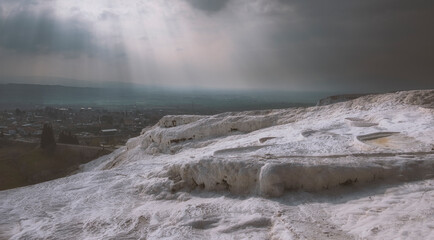 white cotton mountain Pamukkale, in turkey under a stormy sky .with the rays of the sun