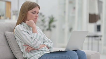 Pensive Young Woman Thinking and Working on Laptop at Home 