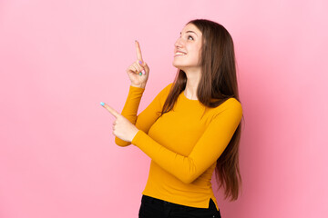 Young caucasian woman isolated on pink background pointing with the index finger a great idea