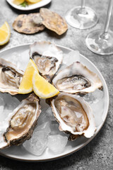 Fresh oysters with lemon and ice on grey table, closeup