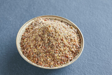 Ground flaxseed in a bowl on a slate background, selective focus.