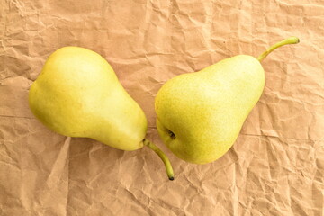 Two organic ripe, light yellow pears on craft paper, close-up, top view.