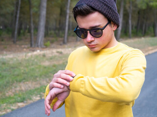 Young Latino boy in yellow sweater looking at his smart watch. New technology concept.