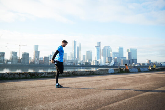 UK, London, Jogger stretching with downtown skyline in background