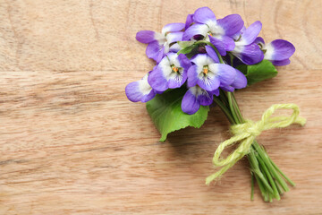 Beautiful wild violets and space for text on wooden table, top view. Spring flowers
