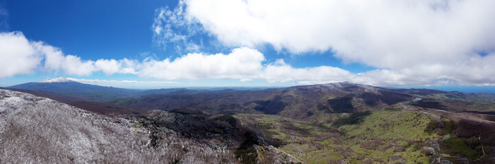 180 degree photo of the beech forest of the Nebrodi mountains in Sicily during a light snowfall in early spring. View of Etna. Monte Soro and the Aeolian Islands with the Tyrrhenian Sea. 