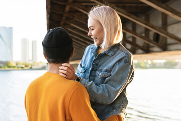Stylish teenage couple having a date under a bridge at sunset