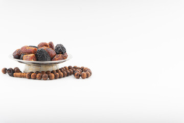 Dates or kurma fruits and rosary beads or Tasbih on white background. Ramadan Kareem and Islamic Concept