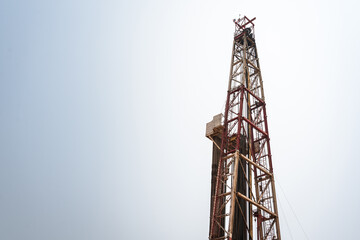 Oil drilling rig derrick platform structure with blue sky background. Heavy industrial operation and energy business photo.