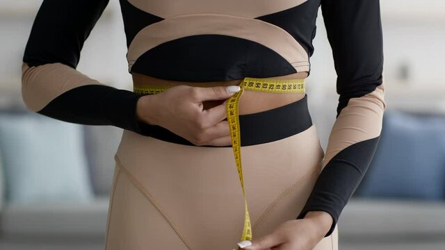 Black Lady Measuring Waist With Tape Standing At Home, Cropped
