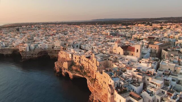 polignano a mare aerial view drone flying backwards over old town at sunrise,famous town on the sea bari puglia italy