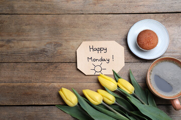 Happy Monday message, aromatic coffee, cupcake and tulips on wooden table, flat lay