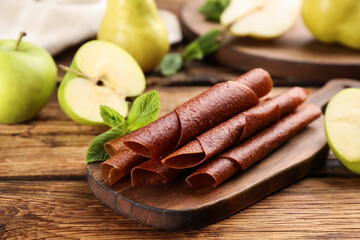 Composition with delicious fruit leather rolls on wooden table, closeup
