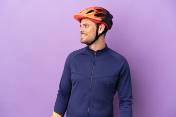 Young Brazilian cyclist man isolated on purple background looking side